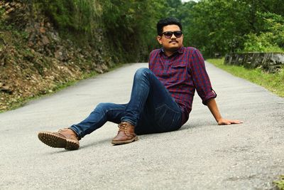 Portrait of young man sitting on road