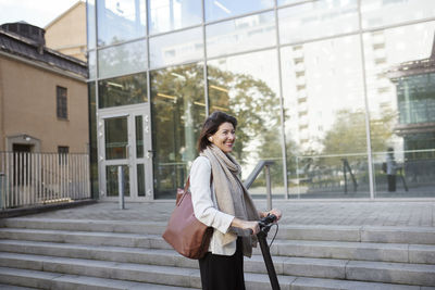 Businesswoman riding electric push scooter