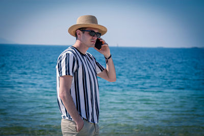 Relaxed man walking on the beach talking on the phone