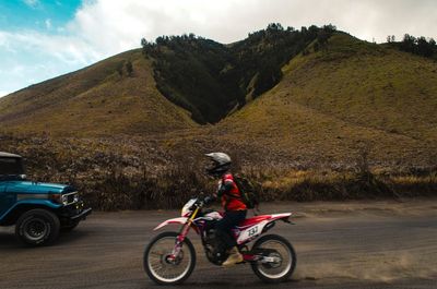 Man riding motorcycle on road against sky