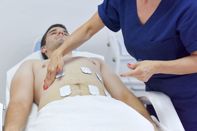 Midsection of friends lying on bed