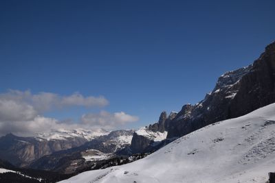 Scenic view of snow covered mountains against blue sky