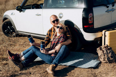 Young couple sitting on car