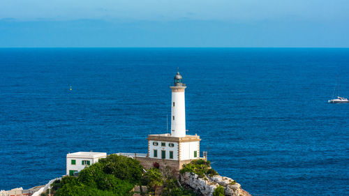 Lighthouse by sea against clear sky