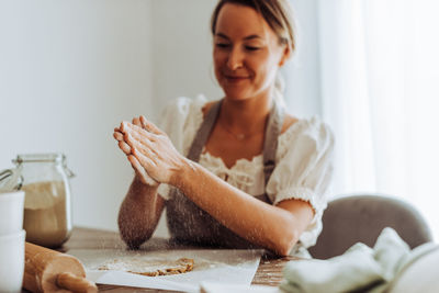 Caucasian woman sprinkling flour on dough while making cookies