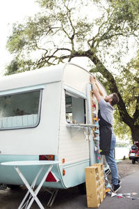 Full length side view of male owner hanging bunting on food truck