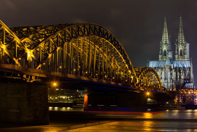 Illuminated bridge over river at night