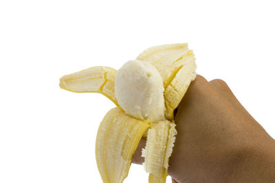 Close-up of hand holding lemon over white background