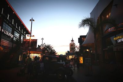 People on street amidst buildings in city against sky