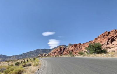 Road leading towards mountains against blue sky