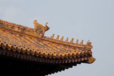 Low angle view of statues on roof against sky