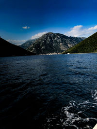 Scenic view of sea and mountains against blue sky