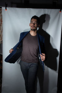 Portrait of young man standing against wall