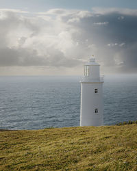 Lighthouse by sea against sky