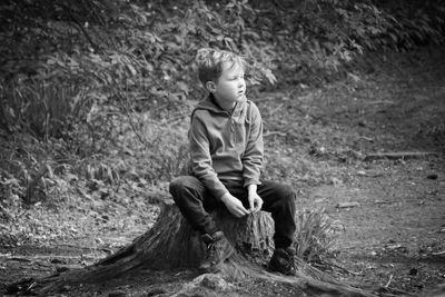 Boy sitting on tree stump