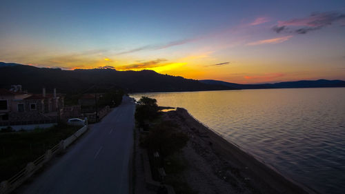 Scenic view of road by city against sky during sunset