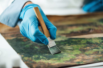 Restoring old oil painting, conservator removing varnish from an oil painting