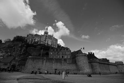 People in front of historical building against cloudy sky mont saint michel