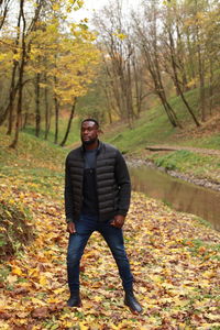 Portrait of young man standing in forest during autumn