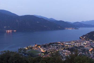 High angle view of illuminated city by sea against sky