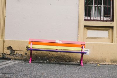 Empty bench against wall in city
