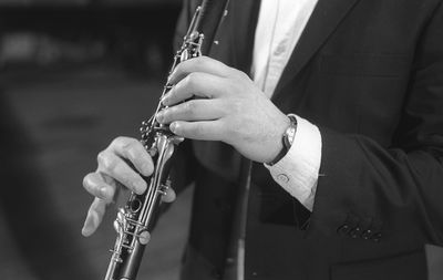 Midsection of man playing clarinet