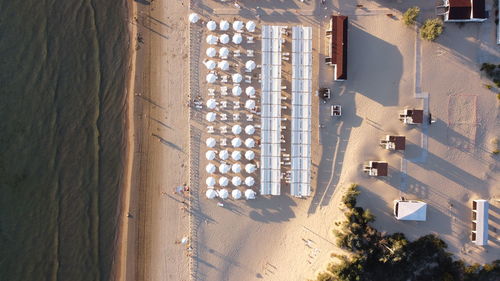 Sun loungers under umbrellas stand on the coast of the sea, beach season, vacation at sea