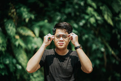 Portrait of young man standing against tree