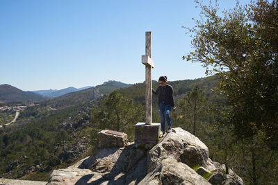 Full length of woman standing on rock against sky