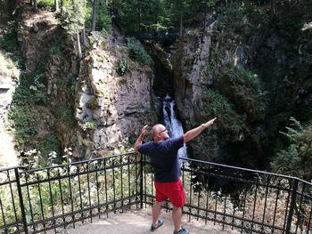 Rear view of man standing on footbridge in forest