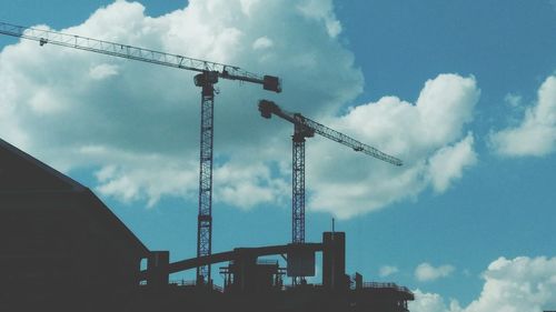 Low angle view of crane at construction site against sky