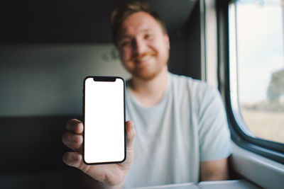 A man using a smartphone while traveling by railway train