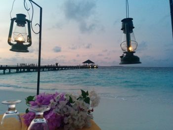 Illuminated street light by sea against sky