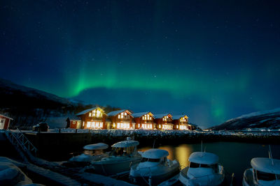 Illuminated buildings by sea against sky at night