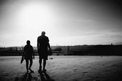 Rear view of silhouette people walking on beach