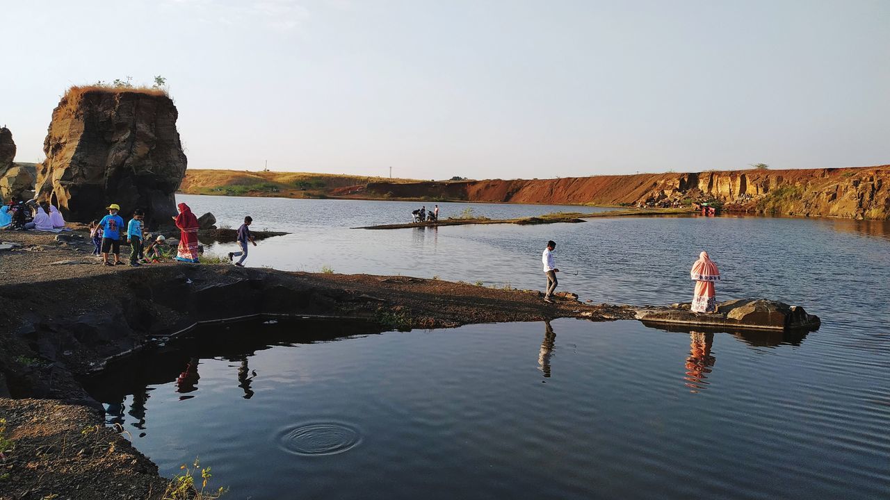 PEOPLE ENJOYING AT BEACH AGAINST CLEAR SKY