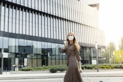 Young woman standing against wall in city