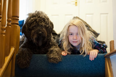 Portrait of girl with dog lying at home