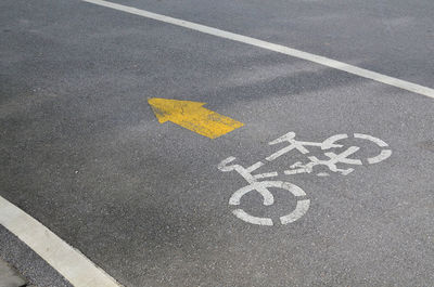 High angle view of arrow and bicycle sign on road