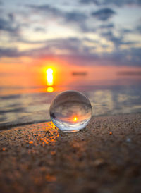 Close-up of water on beach against sky during sunset