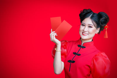 Portrait of smiling young woman against red background