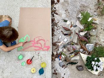 High angle view of boy painting on cardboard outdoors