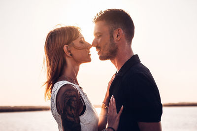 Couple kissing against sky during sunset