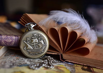 Close up of old book and pocket watch on table
