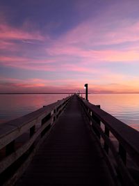 Pier over sea against sky during sunset