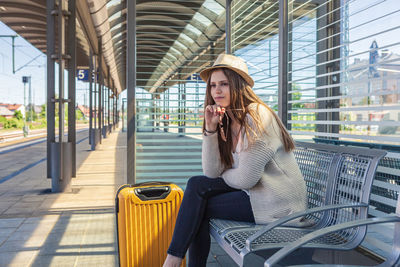 Thoughtful teenage girl sitting at railroad station platform