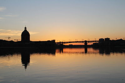 Silhouette of church at riverbank during sunset