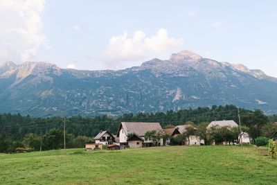 Houses on field by mountains against sky