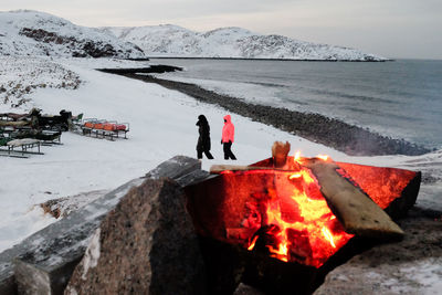 Rear view of people standing on snow covered mountain