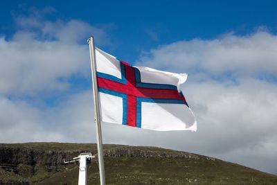 Low angle view of flag on mountain against sky